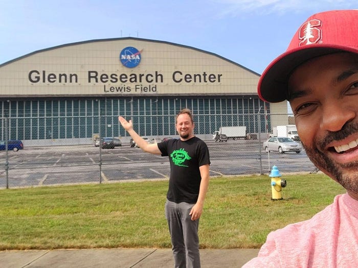 two men stand in front of the Glenn Research Center